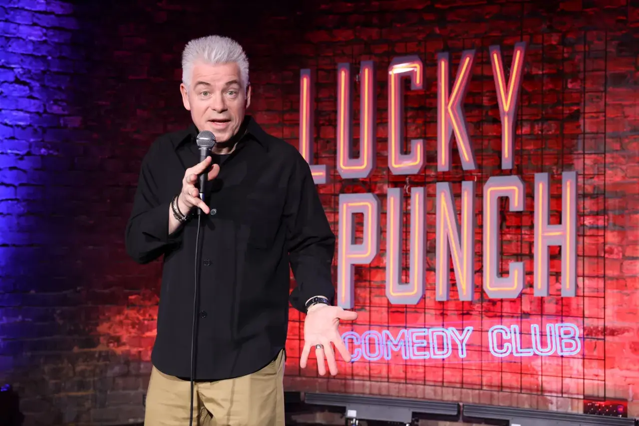 Ein Comedian mit grauem Haar steht auf der Bühne des "Lucky Punch Comedy Club" und erzählt Witze.