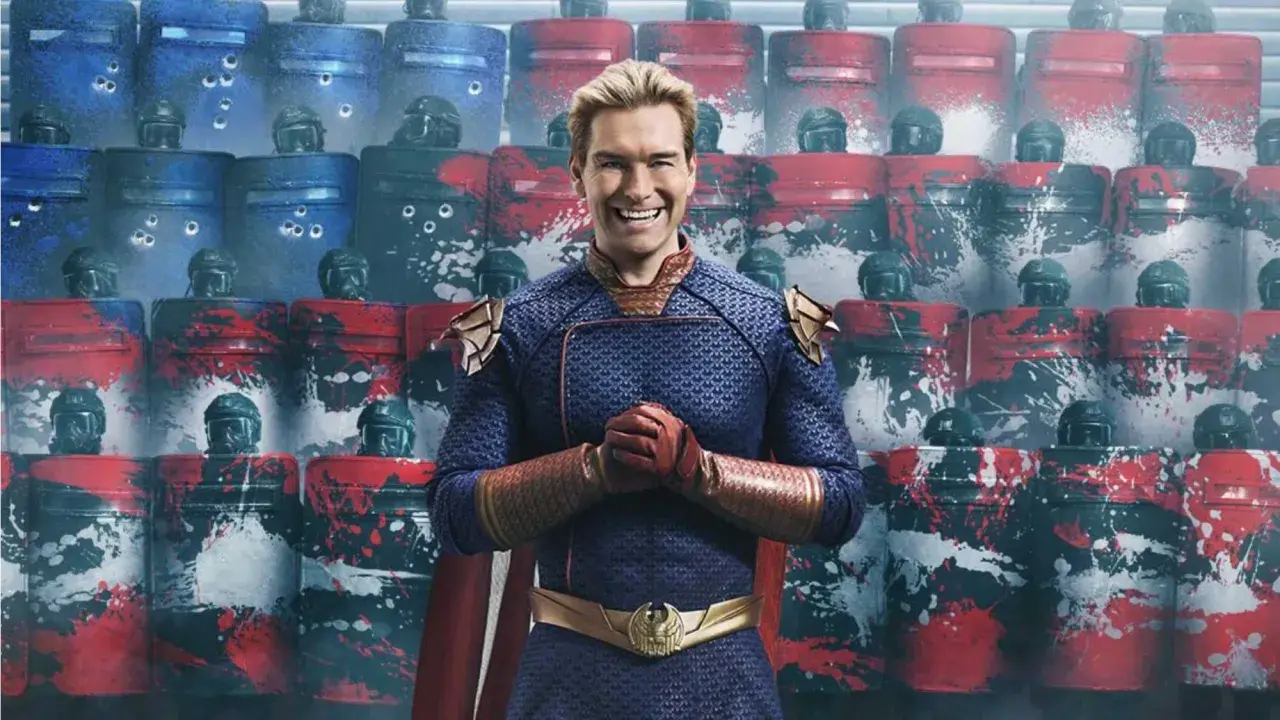 Homelander, Teil der Besetzung von The Boys, steht vor einer Reihe von Riot-Schutzschilden, die mit roten und blauen Farbspritzern verziert sind.