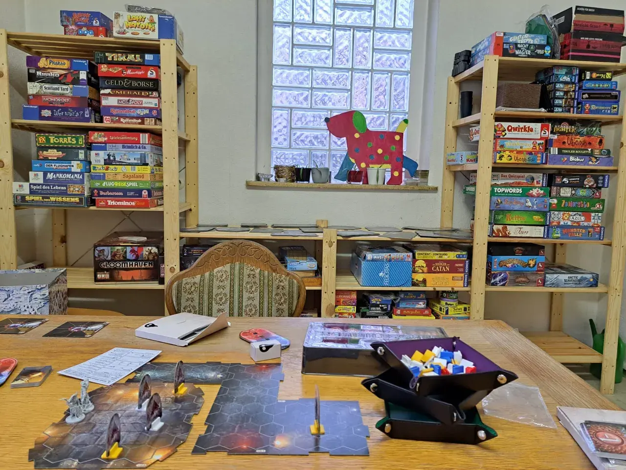 Regale voller Brettspiele für sprachspiele erwachsene. Ein Spielbrett mit Figuren liegt auf dem Tisch.