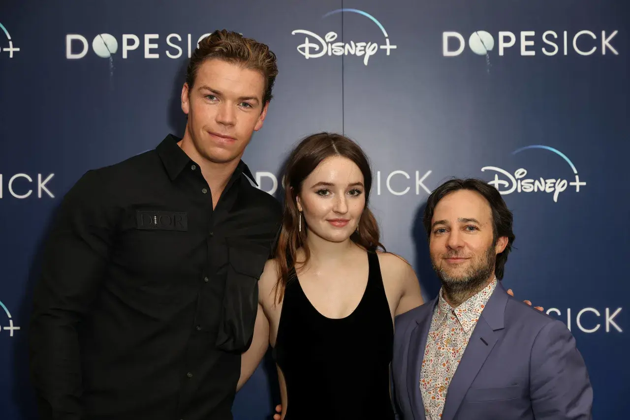 Die Besetzung von Dopesick: Will Poulter, Kaitlyn Dever und Michael Keaton posieren vor dem Disney+ Logo.