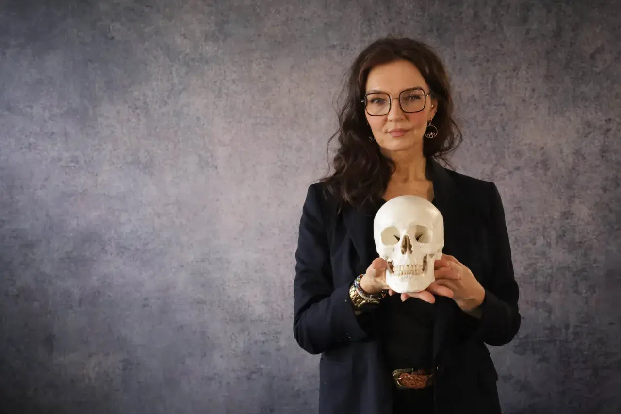 Frau mit Brille hält Totenkopf. Ein gutes stegreifrede beispiel, um über Vergänglichkeit zu sprechen.
