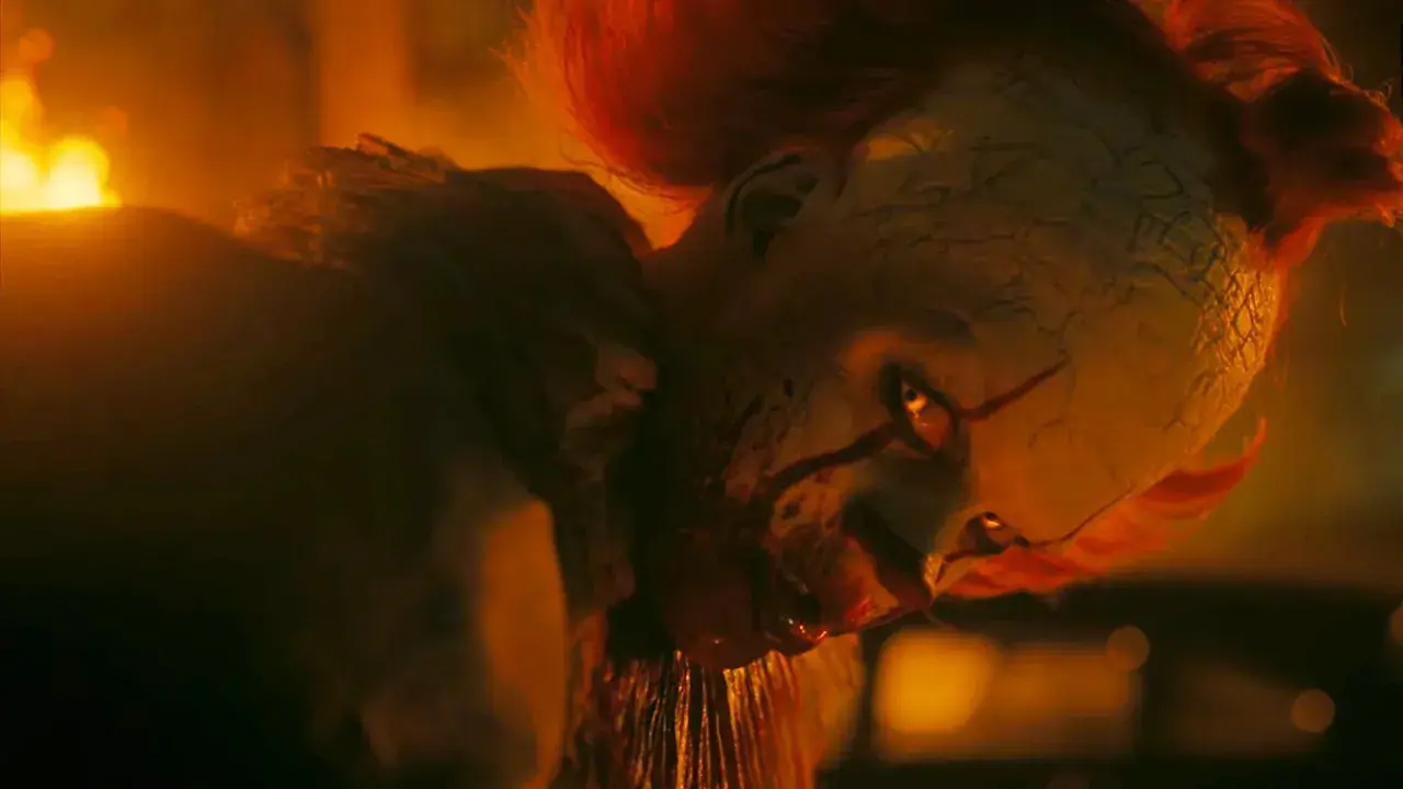 Pennywise, der Clown, blickt mit leuchtenden Augen aus dem Feuer. Willkommen in Derry, wo er auf seine Opfer wartet.