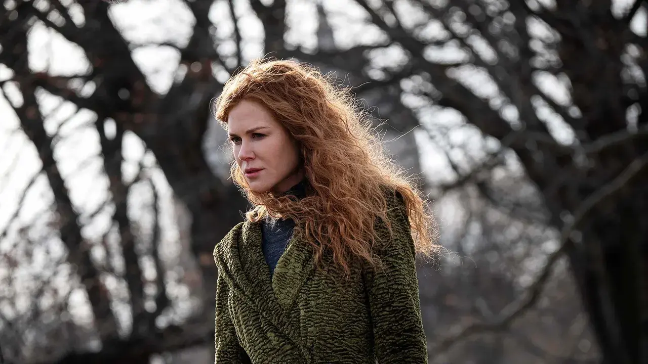 Nicole Kidman mit roten Haaren, im grünen Mantel, blickt nachdenklich in die Ferne. Ein Moment des "the undoing" in der Natur.