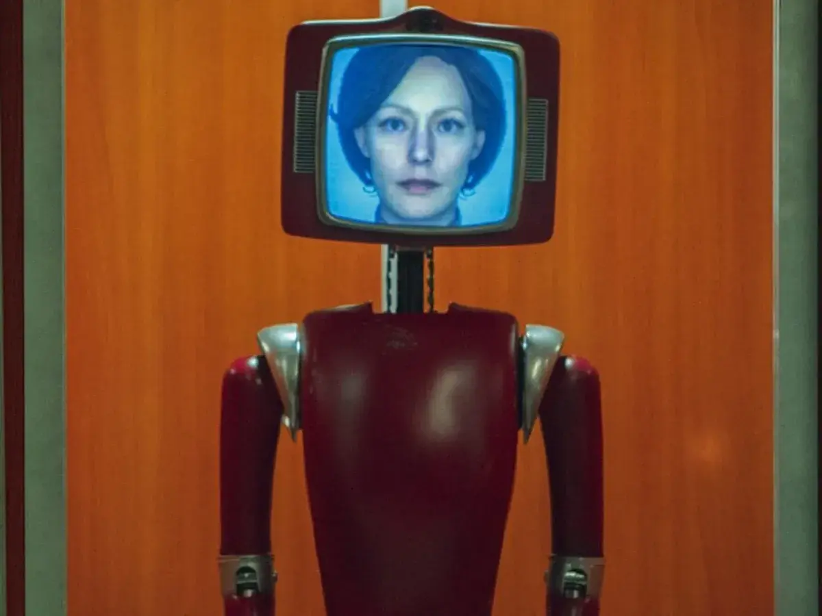 Ein roter Roboter mit einem Bildschirm, auf dem das Gesicht einer Frau zu sehen ist. Dies ist die Besetzung von Cassandra.