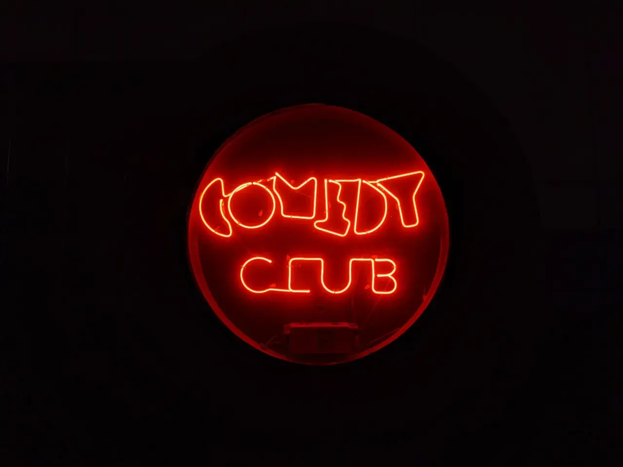 Rotes Neonschild "COMEDY CLUB" im Dunkeln. Ein Ort, an dem die Bedeutung von Kabarett durch Lachen und Unterhaltung lebendig wird.