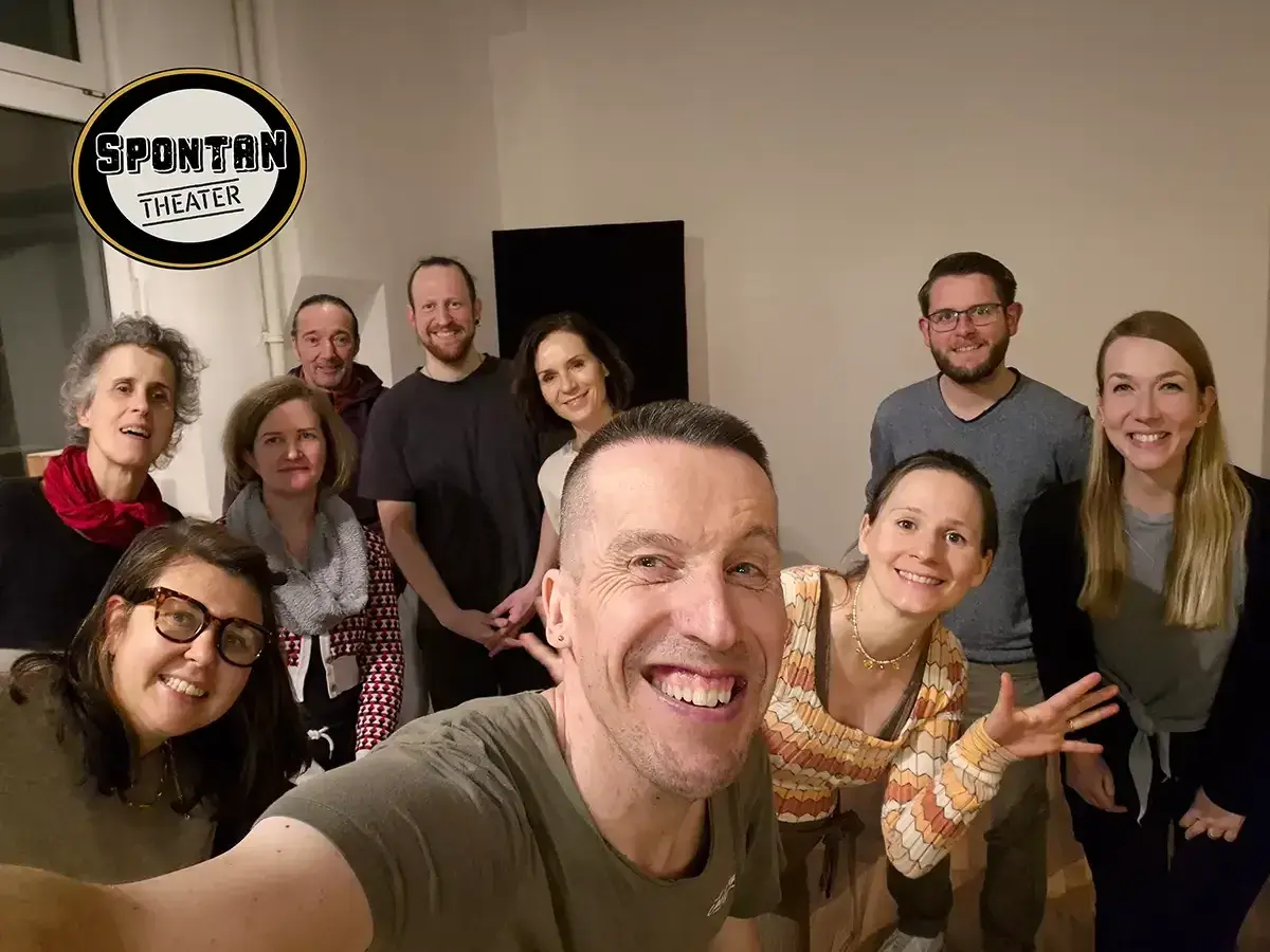 Gruppe lacht in die Kamera, bereit, die **improvisieren Bedeutung** im Spontan Theater zu leben.