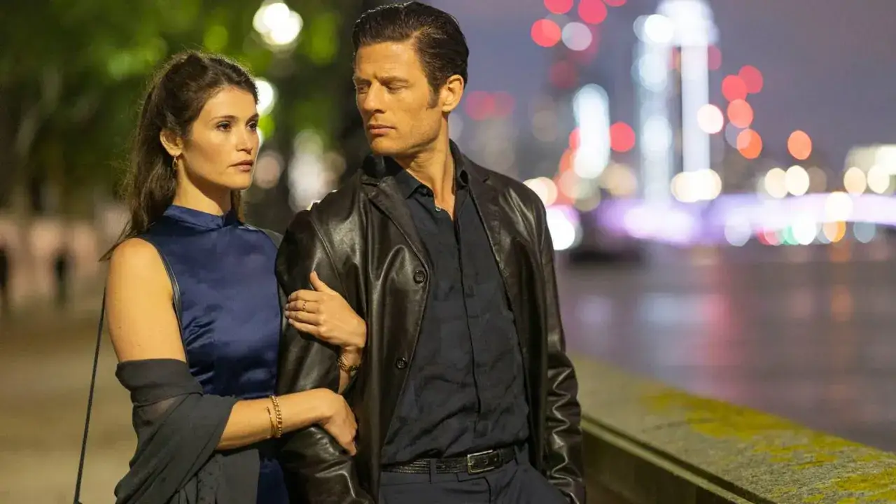 Ein Mann in Lederjacke und eine Frau in blauem Kleid gehen nachts am Fluss entlang. Ein romantischer Moment im rogue agent film.