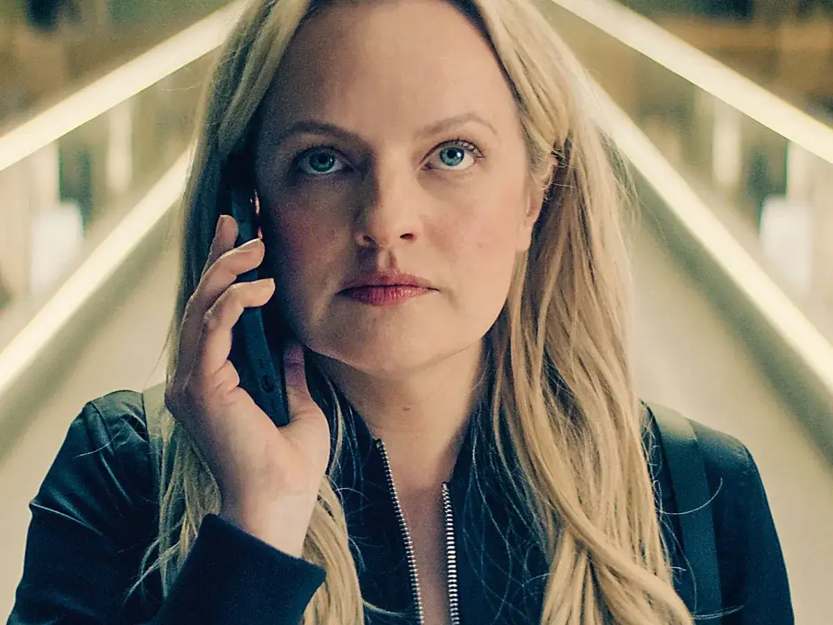 Eine Frau mit blonden Haaren und blauen Augen telefoniert. Ihr Blick ist intensiv, als w&uuml;rde sie hinter einem Schleier der Geheimnisse agieren.
