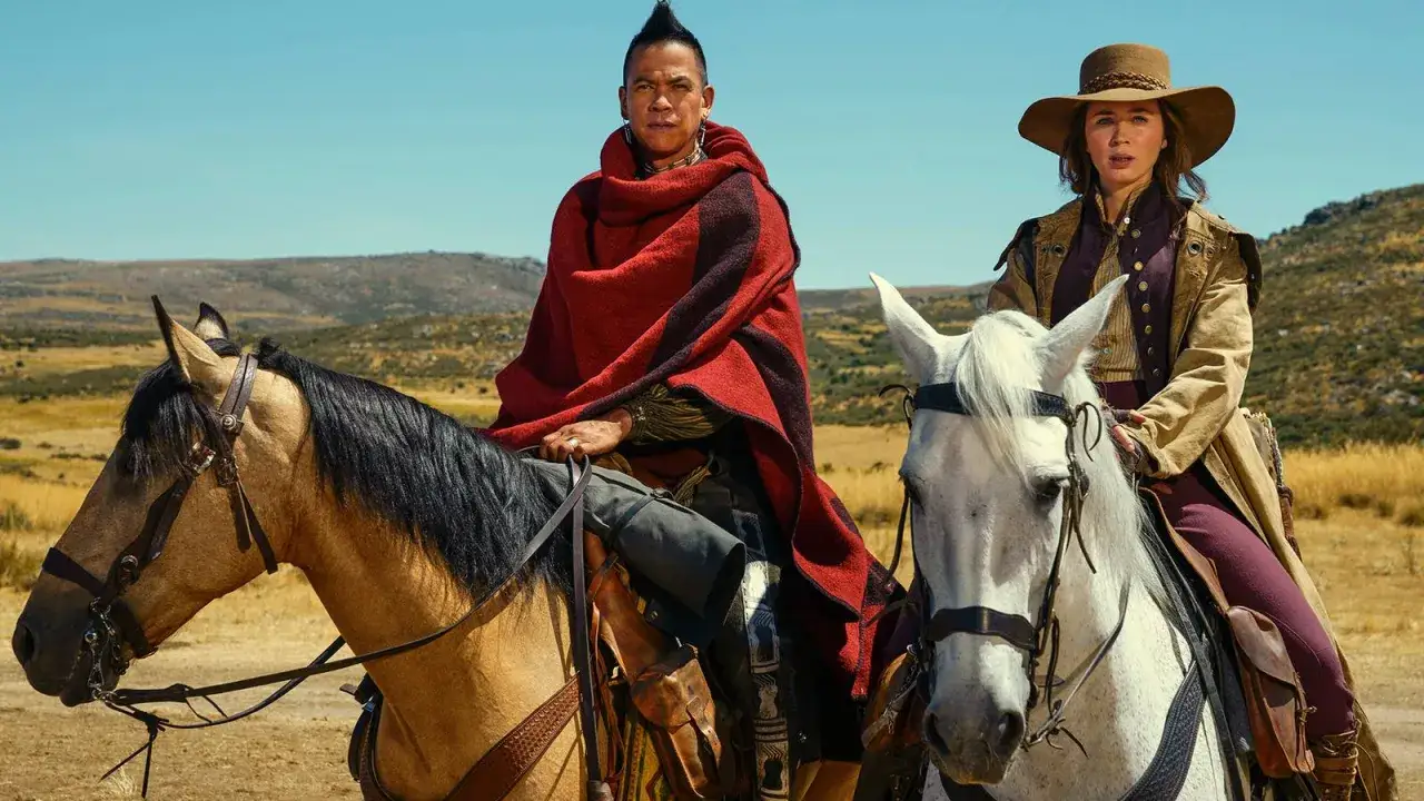 Ein Mann mit rotem Poncho und eine Frau mit Hut reiten auf Pferden durch eine trockene Landschaft. Die englische Serie verspricht Abenteuer.