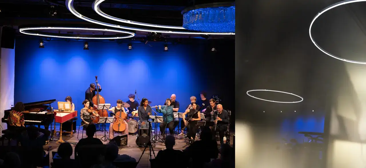 Ein Orchester spielt auf einer Bühne vor blauem Hintergrund. Verschiedene Musiker spielen Instrumente wie Klavier, Cello, Kontrabass und Flöte. Dies zeigt einige der vielen Berufe im Theater.