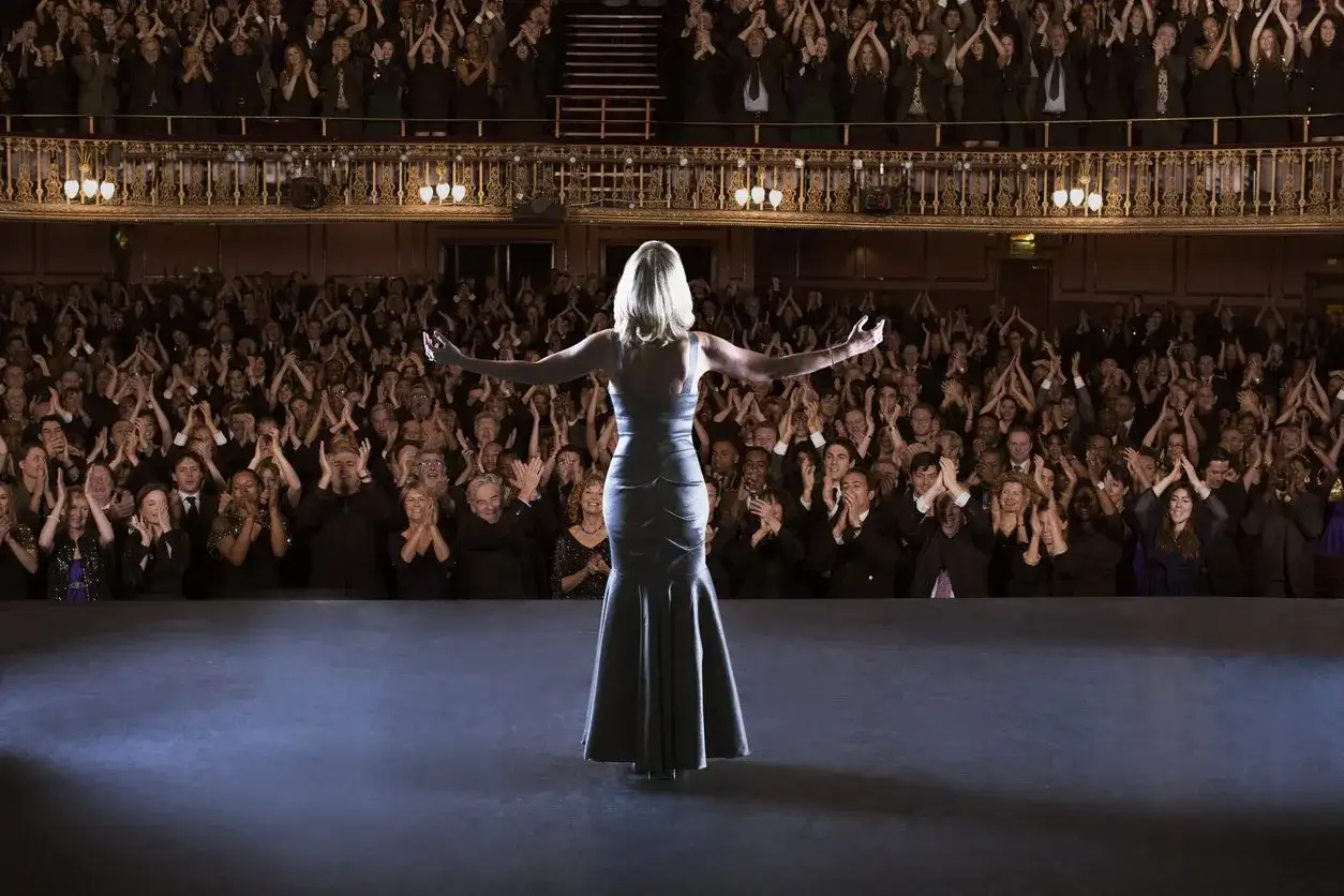 Eine Sängerin verbeugt sich vor tosendem Applaus im Theater. Ein Moment, der an ein großes Musical erinnert.