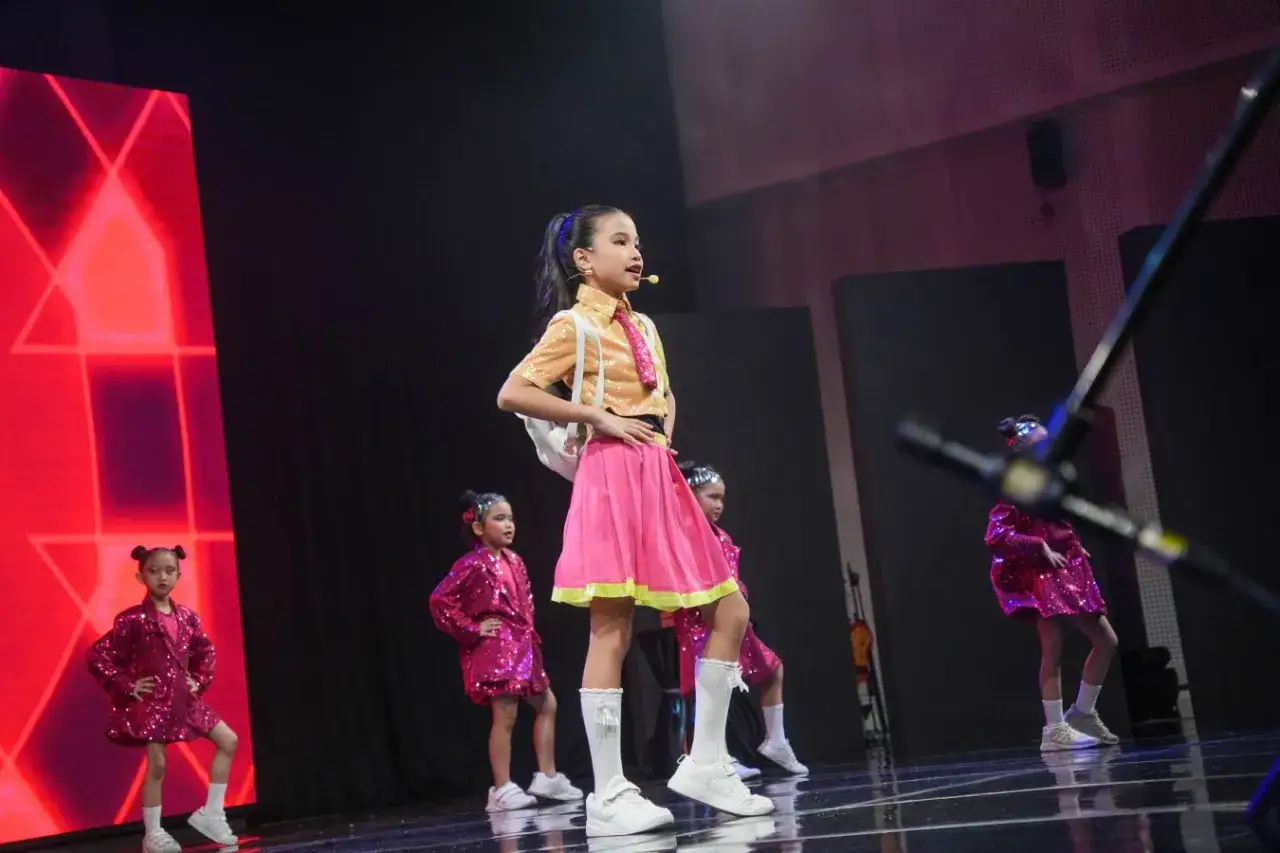 Kinder üben für ihren großen Auftritt. Sie spielen Theater und tanzen in glitzernden Kostümen auf einer Bühne.