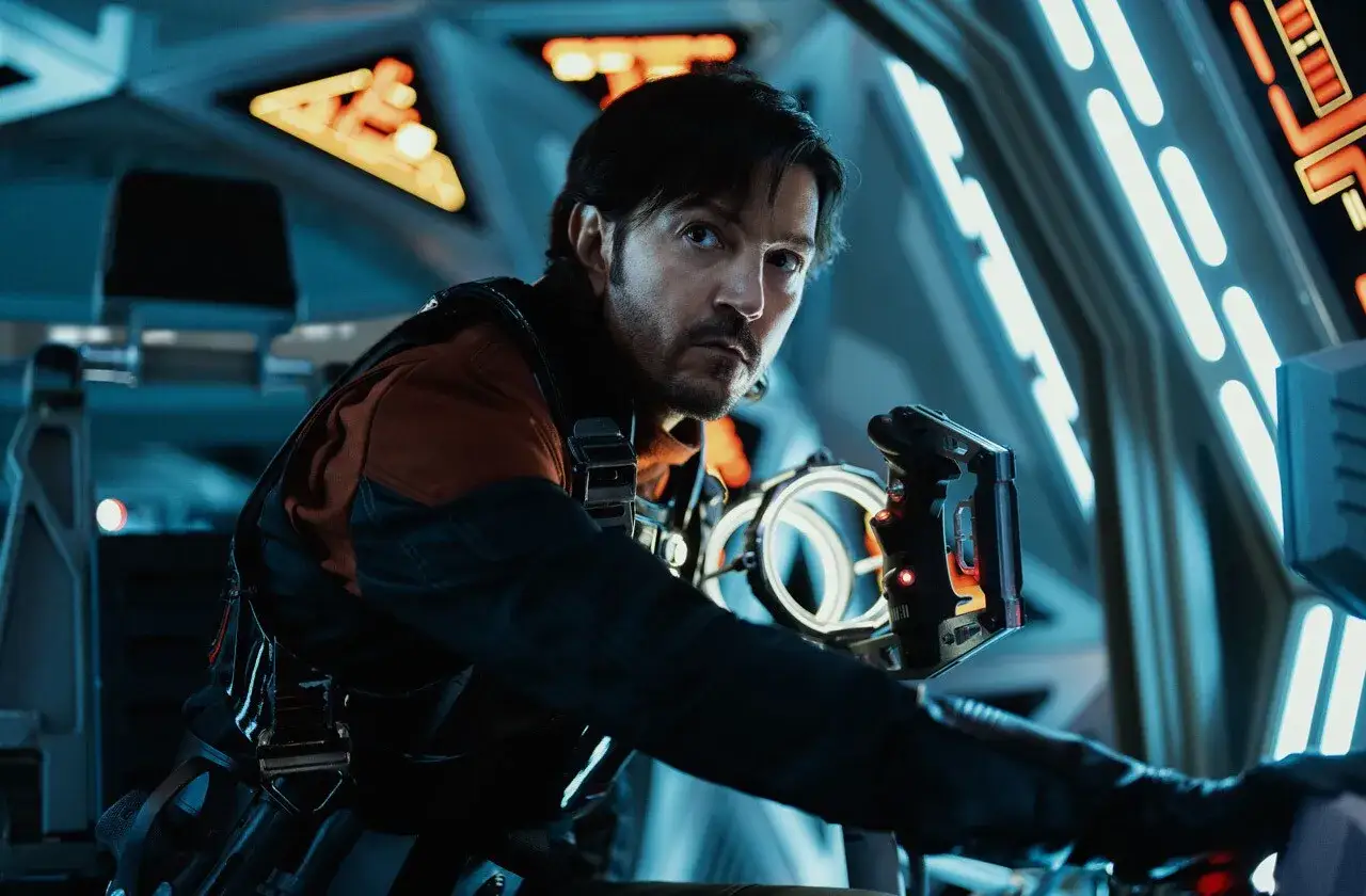 Cassian Andor in der Andor Serie, mit einem Gerät in der Hand, blickt angespannt in die Ferne.