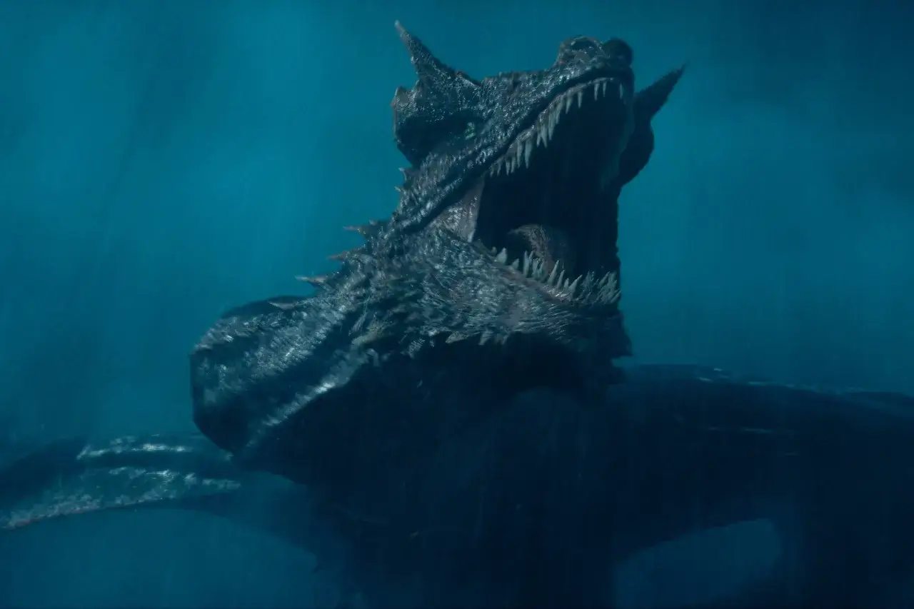 Ein furchterregender Drache mit weit aufgerissenem Maul und spitzen Z&auml;hnen, ein ikonischer Anblick aus den Folgen von House of the Dragon, taucht aus dem tiefblauen Wasser auf.