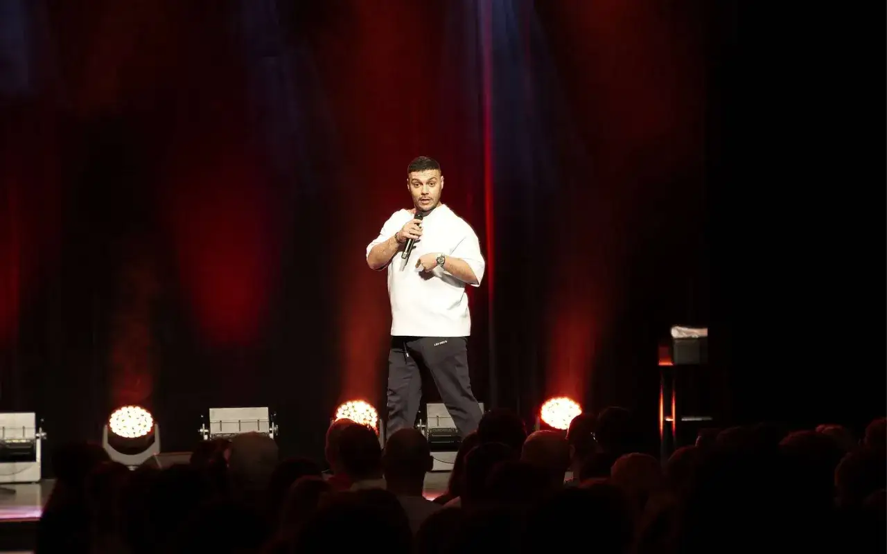 Ein Comedian steht auf der Bühne, Mikrofon in der Hand, und erzählt Witze, die für ein double entendre gut sind.