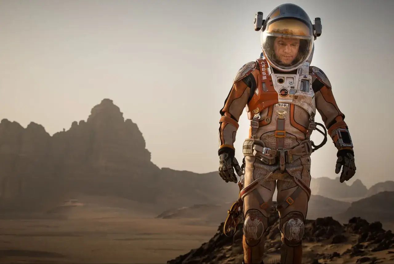 Ein Astronaut in einem orange-weißen Raumanzug steht auf dem Mars. Ein Szene aus dem