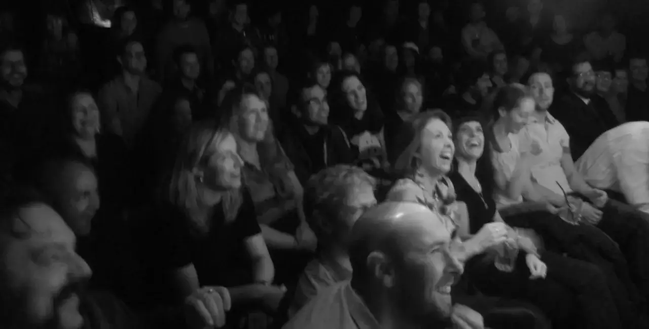 Publikum lacht laut &uuml;ber einen gag witz. Viele Gesichter strahlen vor Freude.