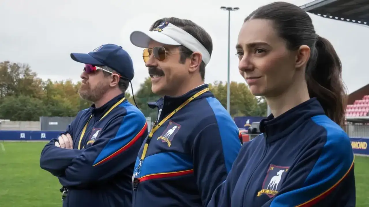 Ted Lasso und sein Team blicken auf das Spielfeld.