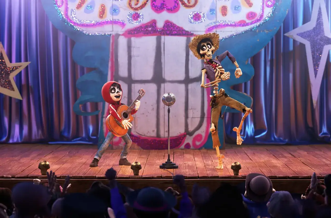 Miguel spielt Gitarre, w&auml;hrend H&eacute;ctor im Stil des Coco film tanzt. Sie stehen auf einer B&uuml;hne vor einem bunten Vorhang.